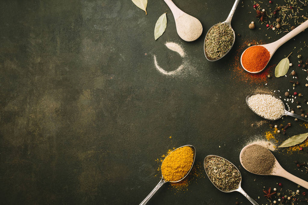 Spices and herbs over black stone background. Top view. Copy space - Zdjęcie, obraz