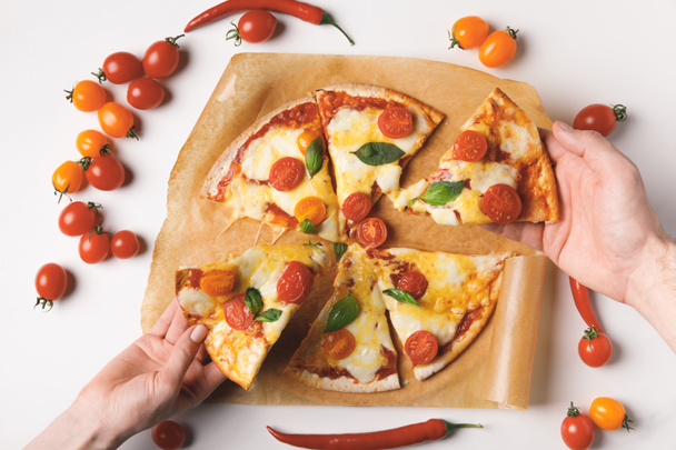 abgeschnittenes Bild von Frau und Mann, die hausgemachte Pizza auf Weiß nehmen - Foto, Bild