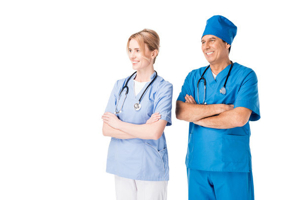 Médico y enfermera sonriente con estetoscopios de pie con los brazos cruzados aislados en blanco
 - Foto, Imagen