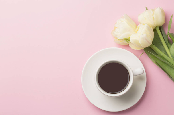 Tulips and coffee on pink background. Flat lay with flowers and drink with space for text. Greeting card. Happy day concept - 写真・画像