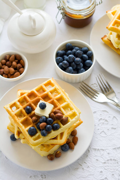 Healthy breakfast. Belgian waffles with butter, blueberry and nuts on white tablecloth. Selective focus - Fotoğraf, Görsel