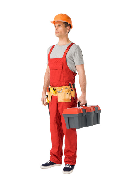 Constructor guapo en uniforme con correa de herramientas que sostiene la caja de herramientas aislada en blanco
 - Foto, Imagen