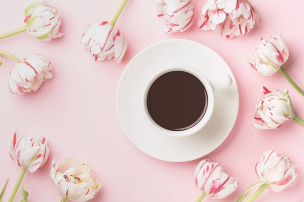 Spring morning concept. Flat-lay of cup of coffee and flowers over light pink background, top view with space for your text - Foto, Imagem