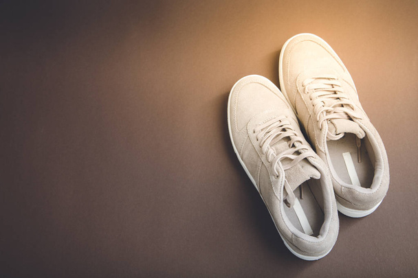 Pastel beige sneakers on a brown background. Flat lay, minimal b - Foto, afbeelding