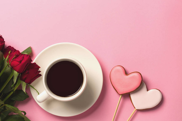Gingerbread hearts, red roses and a cup of coffee on a pink back - 写真・画像