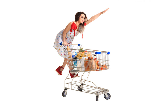 Woman with shopping cart full with products isolated over white background - Fotoğraf, Görsel