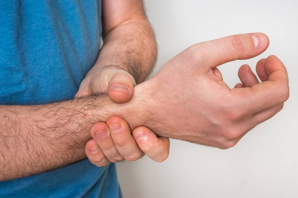 Man met pols pijn houdt zijn pijnlijke hand - Foto, afbeelding