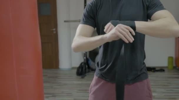 Close up of male boxer wrapping boxing bandages around his hands in the training gym - Video