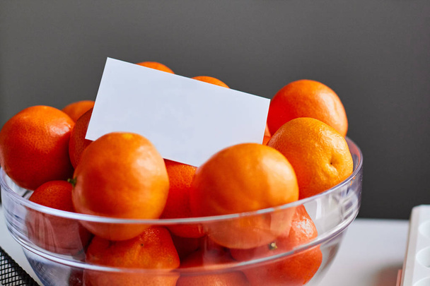 Біла листівка в мисці, повна мандаринів
 - Фото, зображення