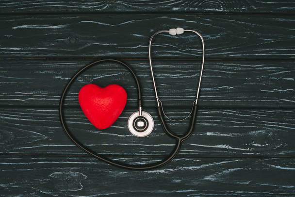płaskie lay z czerwonym sercem i stetoskop na ciemne drewniane stołowe, świat zdrowia dzień koncepcji - Zdjęcie, obraz