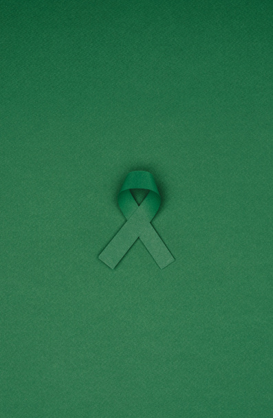 close up view of green awareness ribbon for Scoliosis, mental health symbol isolated on green tabletop - Φωτογραφία, εικόνα