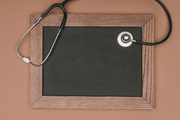 top view of blank chalkboard and stethoscope isolated on beige surface, world health day concept - Photo, Image