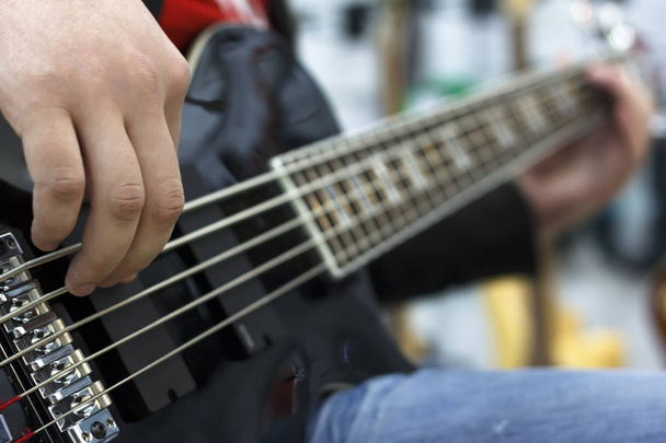 az ujjak zenész játszik basszus gitár a színpadon közelről - Fotó, kép