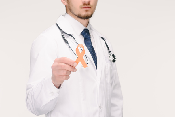 cropped shot of doctor with stethoscope showing orange leukemia, kidney cancer, multiple sclerosis RSD awareness ribbon isolated on white - Photo, Image