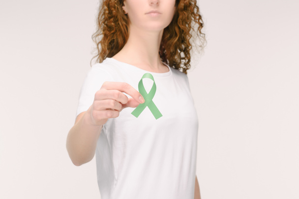 cropped shot of woman showing green awareness ribbon for Adrenal Cancer, Aging research awareness, BiPolar Disorder isolated on white - Photo, Image