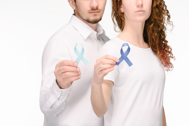 Μερική άποψη του ζευγάρι κρατώντας κορδέλες από διαφορετικά χρώματα που απομονώνονται σε λευκό, έννοια του καρκίνου του παχέος εντέρου - Φωτογραφία, εικόνα