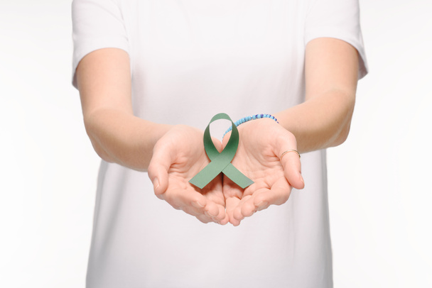 abgeschnittene Aufnahme einer Frau mit grünem Bewusstseinsband für Skoliose, Symbol für psychische Gesundheit in den Händen isoliert auf weiß - Foto, Bild