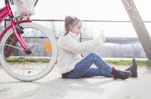 küçük kız açık havada Bisiklet ve oyuncak ayı ile oynama - Fotoğraf, Görsel