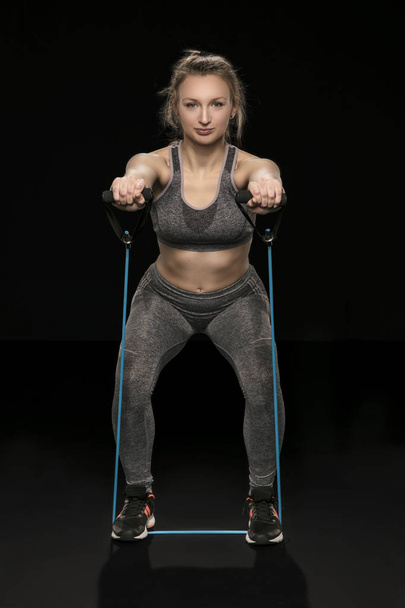 athletic woman stretches elastic rubber, isolated on the black b - Valokuva, kuva