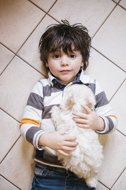 malý chlapec ležící s bílým psem - Fotografie, Obrázek
