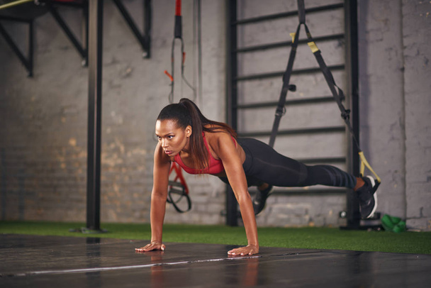 Young woman practicing on floor with trx ropes - 写真・画像