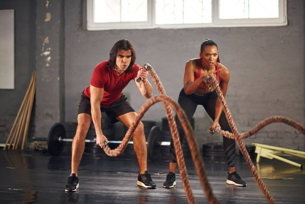 Jeune couple pratiquant avec des cordes dans la salle de gym
 - Photo, image