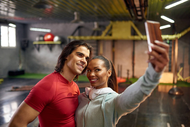 Smiling man and woman making selfie in gym - Photo, image