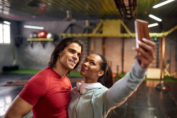 Smiling man and woman making selfie in gym - Фото, изображение