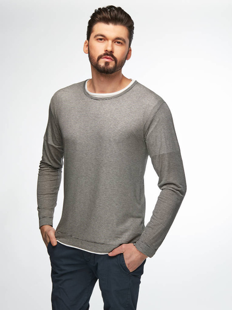 Fashion portrait of handsome male model with dark hair, beard and eyes, wearing grey sriped sweater - Фото, изображение