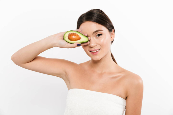 Happy lady holding avocado near clean face and looking camera - Foto, Imagem
