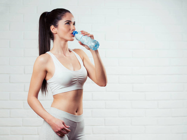 Beautiful, fit, young woman holding a bottle of water - Fotó, kép