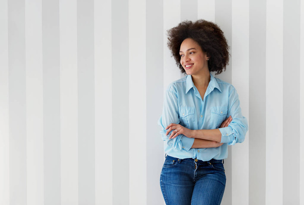Beautiful African American woman smiling, on a striped wall background  - Photo, image