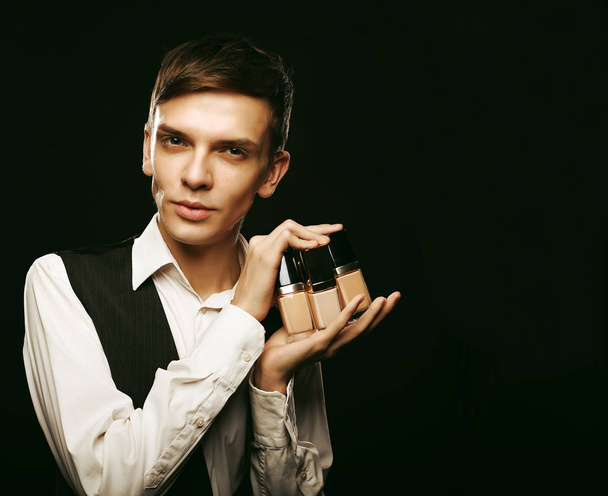 Young male make up artist posing with foundation for make-up - Foto, immagini