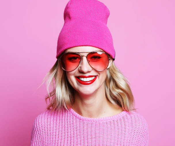 Stylish fashion portrait of trendy casual young woman in pink pulover and hat, - 写真・画像