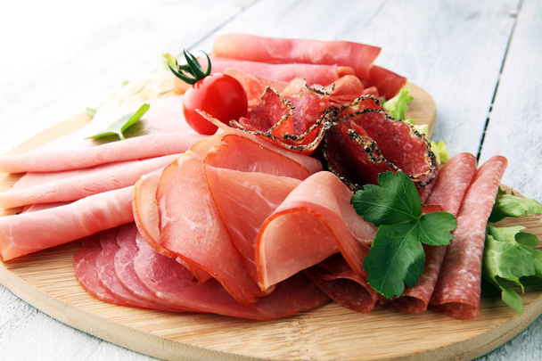 Food tray with delicious salami, pieces of sliced ham, sausage,  - Фото, изображение