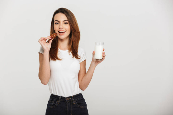 Pretty young woman eating cookie drinking milk. - Zdjęcie, obraz