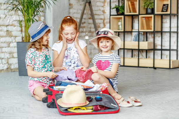 I bambini felici mettono le cose in valigia durante un viaggio. Concetto
 - Foto, immagini