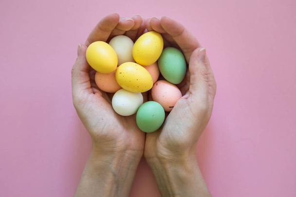 Uova di Pasqua variopinte in mani su sfondo rosa
 - Foto, immagini