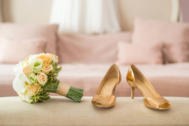 close-up de belo buquê de casamento de flores brancas com sapatos dourados de noiva no fundo borrado
 - Foto, Imagem