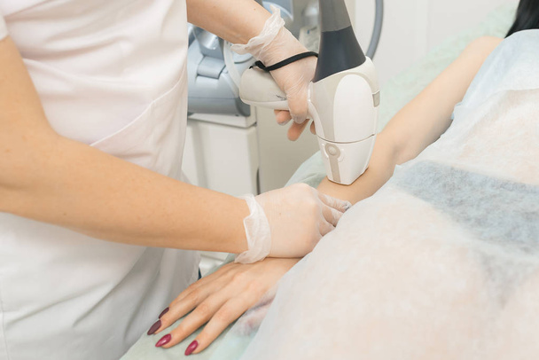 specialist makes client laser hair removal on hands - Foto, immagini