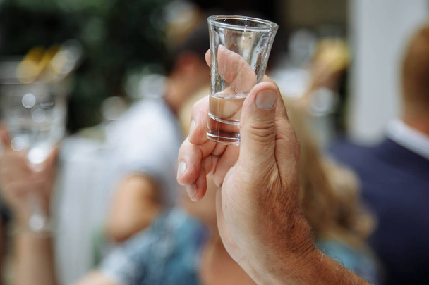 Man's hand holding a glass with vodka. - Foto, Bild