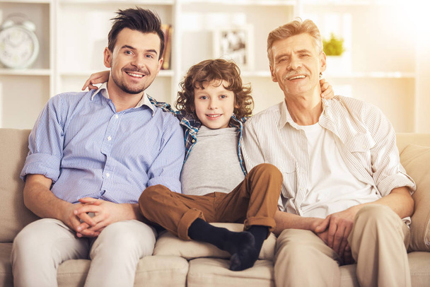 Generation portrait. Grandfather, father and son sitting on sofa - Fotó, kép
