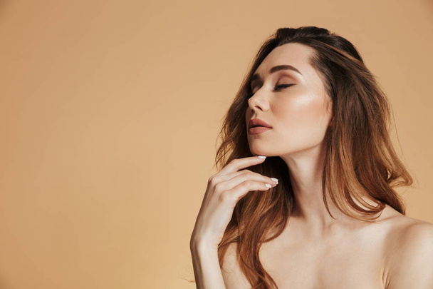 Young woman with closed eyes standing isolated over beige - Foto, imagen