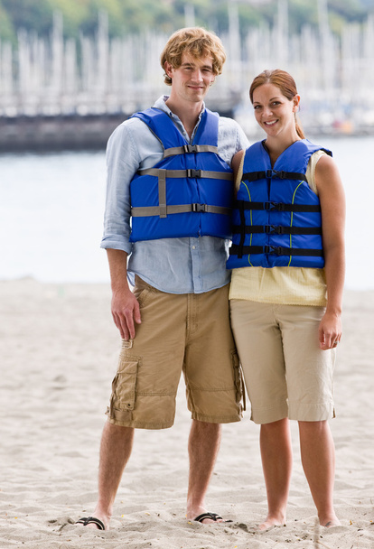 Casal vestindo coletes salva-vidas na praia
 - Foto, Imagem