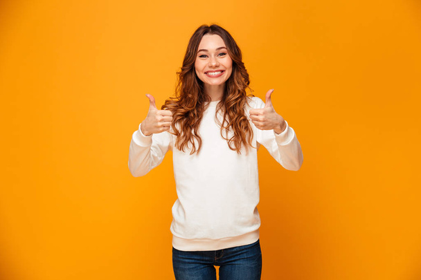 Smiling brunette woman in sweater showing thumbs up - Zdjęcie, obraz