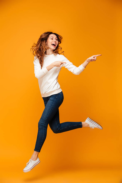 Full length image of Joyful brunette woman in sweater running - 写真・画像