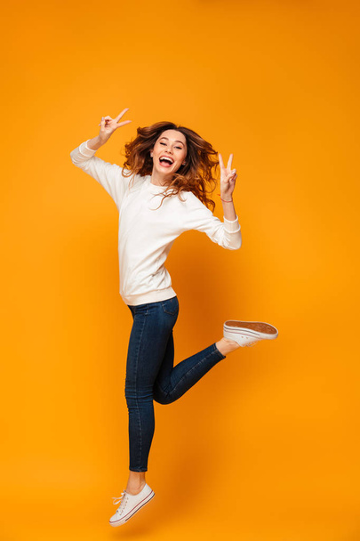 Full length image of Cheerful brunette woman in sweater jumping - Fotoğraf, Görsel