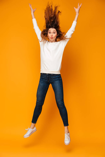 Full length image of Pretty brunette woman in sweater jumping - Фото, изображение