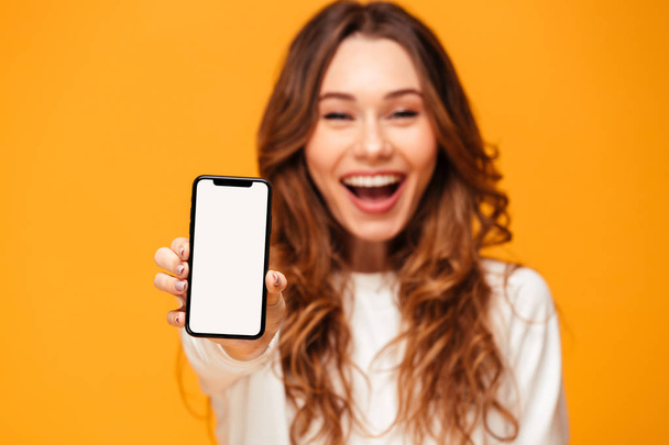Happy brunette woman in sweater showing blank smartphone screen - Фото, зображення