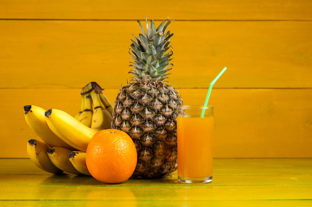 黄色の木製の背景、生鮮食品のトロピカル フルーツ - 写真・画像